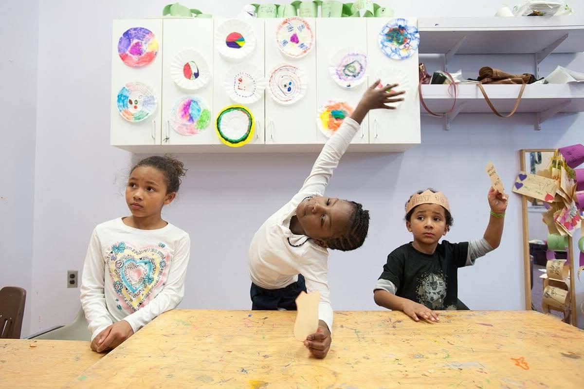 Elementary students at desks raising hands at University of Rochester Mt. Hope Family Center